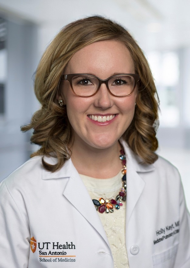 A person wearing glasses and a lab coatDescription automatically generated